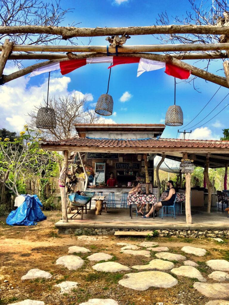 restaurant met daarvoor een pad van grote kiezelstenen met boven in beeld de houten poort