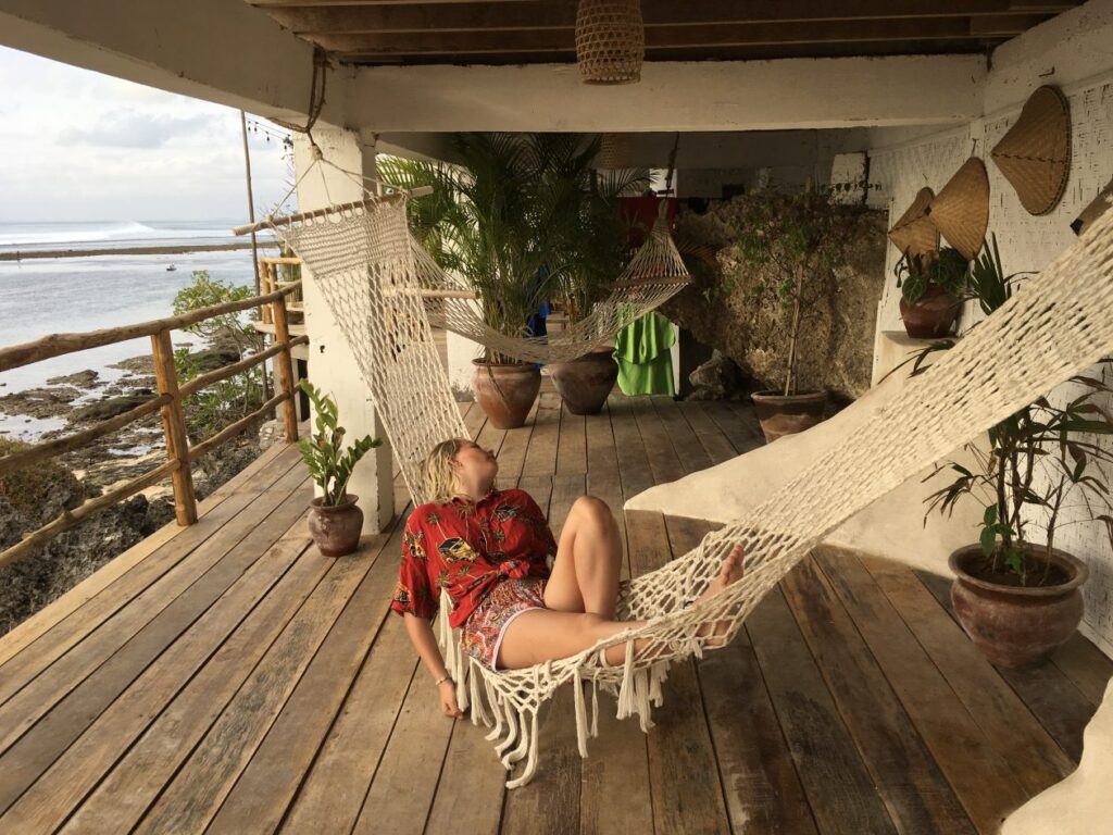 Meisje in hangmat in een hip hotel met uitzicht op zee