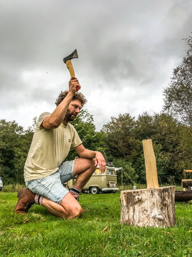 man met hakbijl is hout aan het hakken