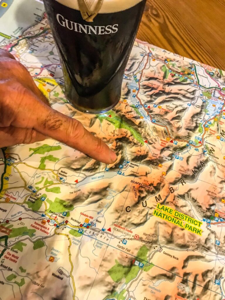 Vinger die wijst op een landkaart met daarnaast een glas bier