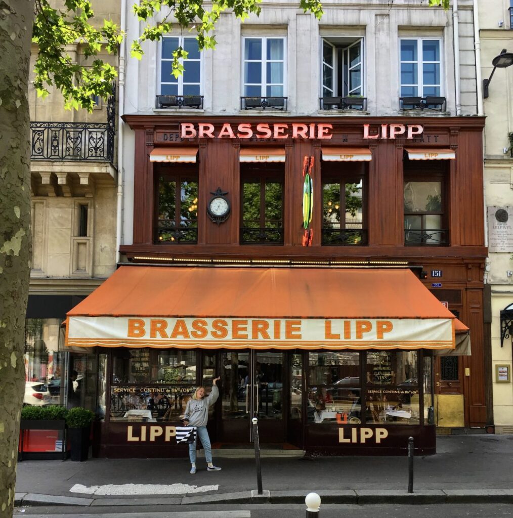 Exterieur van Brasserie Lipp in Parijs met meisje die wijs naar de zonnewering