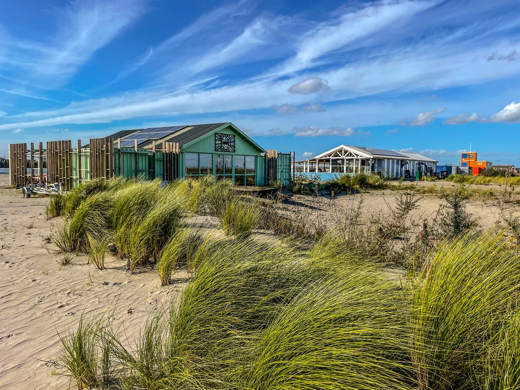 Helmgras op een strand met in de verte Strand cafe's