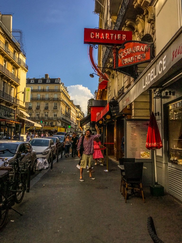 Straat in Parijs met man die op eem neon pijl naar een restaurant wijst