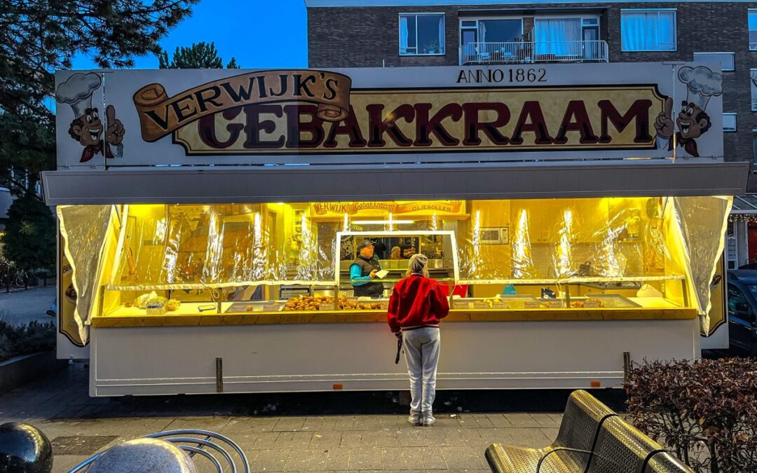 oud hollandse oliebollen kraam op een plein met een vrouw ervoor