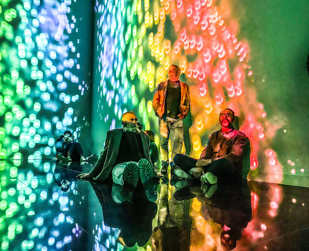 Drie mannen zitten in een lichtshow