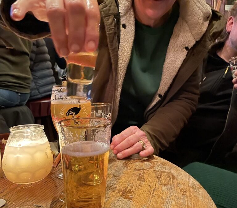 Vrouw in cafe met een glas bier op de voorgrond