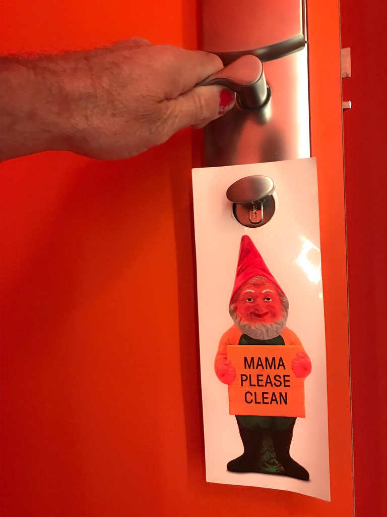 Rode hoteldeur met hand aan de deurknop en een deurkaart met een kabouter erop