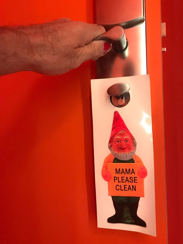 Rode hoteldeur met hand aan de deurknop en een deurkaart met een kabouter erop