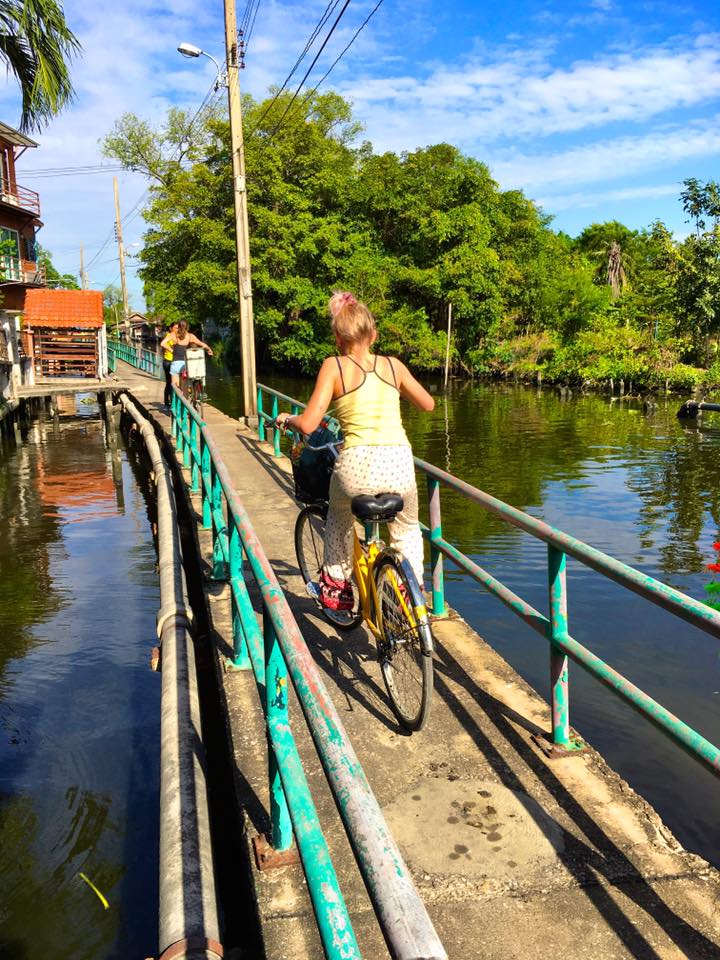 Meisje op een fiets op een smal bruggetje in Bangkok