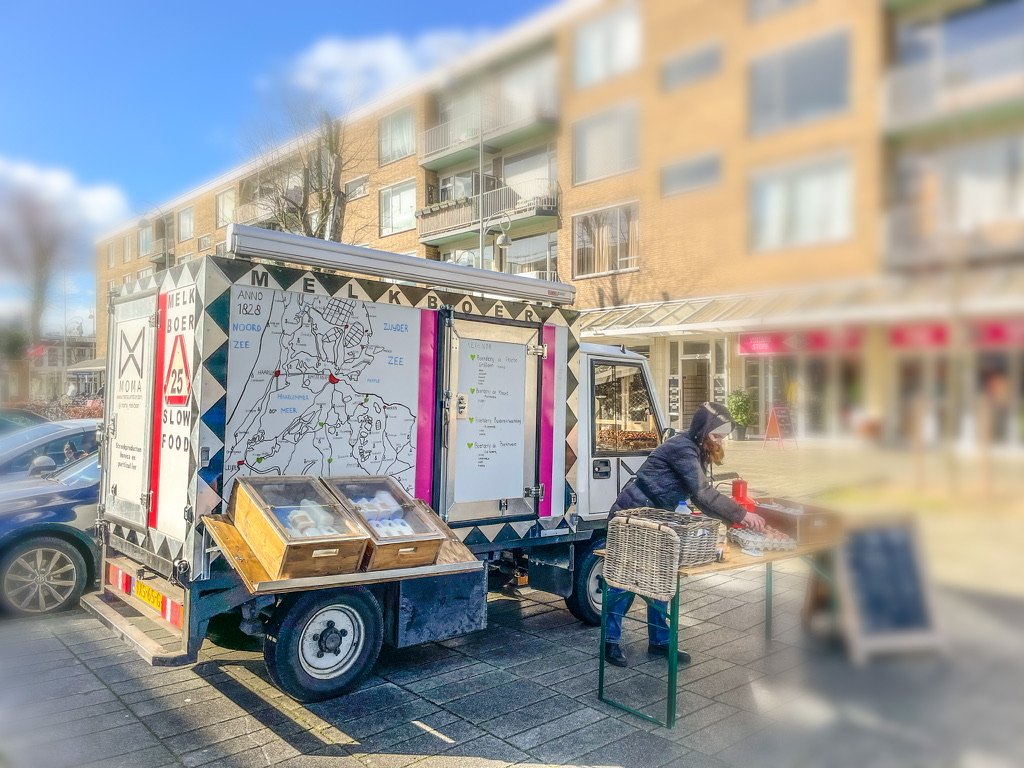 Rijdende Melkkar op een plein met vrouw ervoor