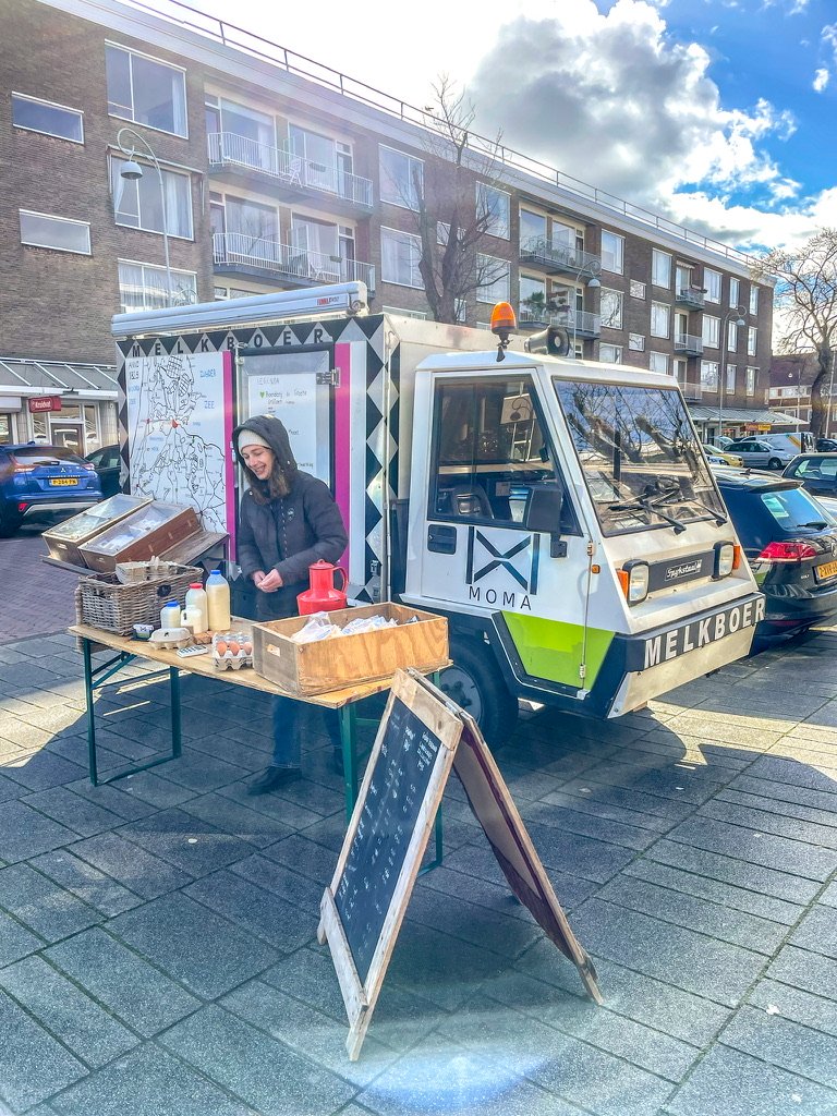 Melkkar op plein met vrouw achter toonbank