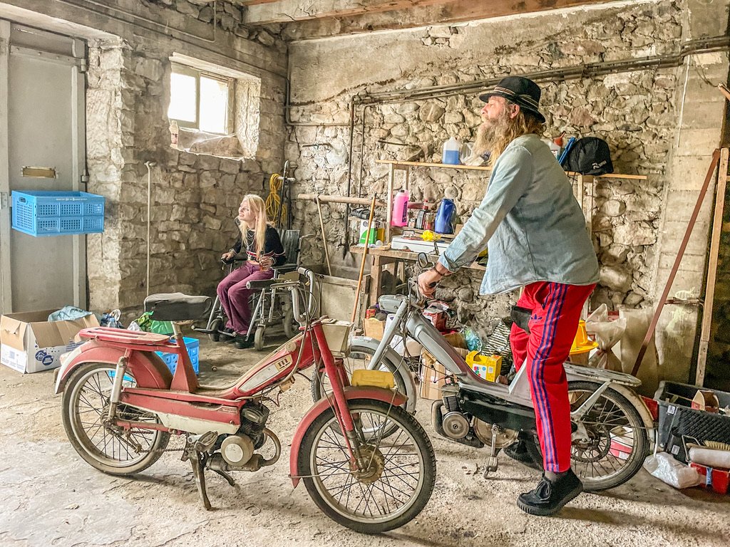 man met hoed op een brommer in de schuur