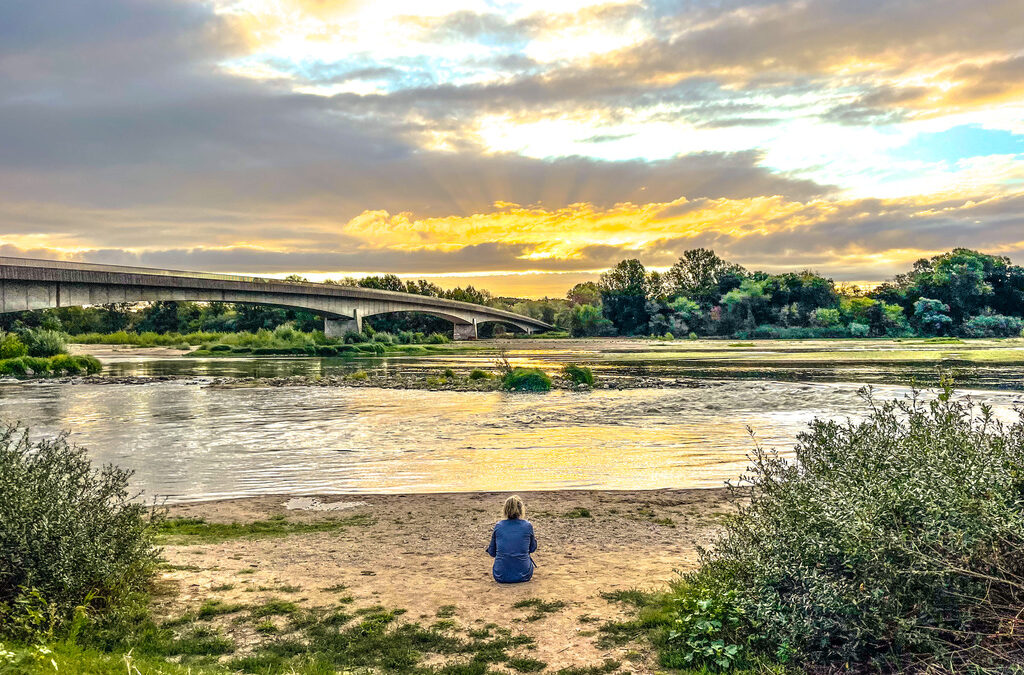 zitten vrouw kijkt naar rivier met links een brug