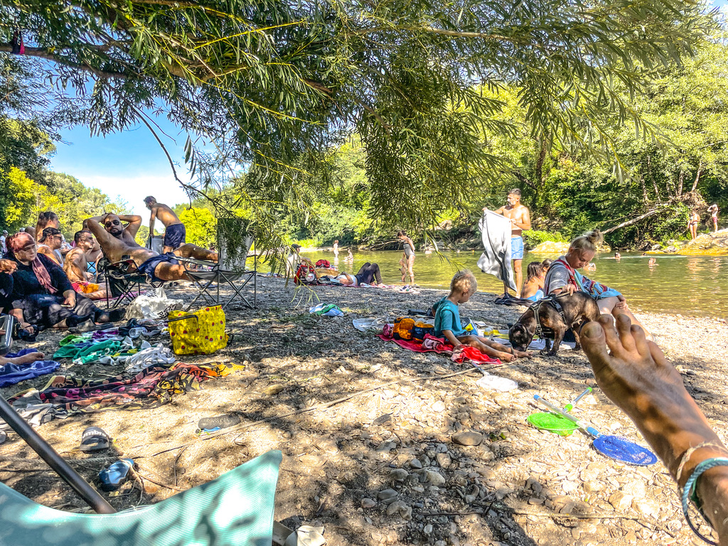 mensen in de schaduw van bomen aan de rivier in de zomer