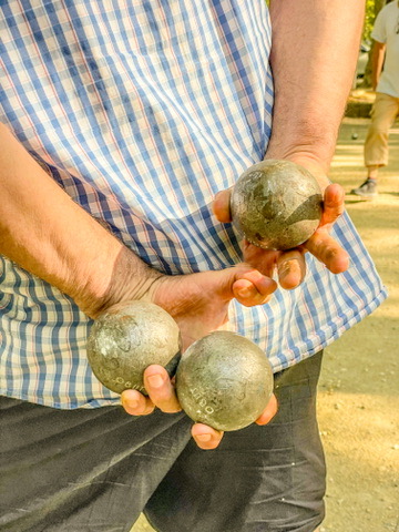 twee handen op de rug met daarin drie petanque ballen