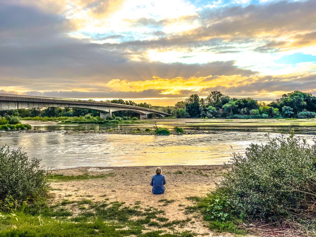 zitten vrouw kijkt naar rivier met links een brug