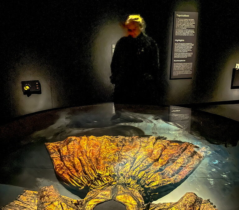 vrouw in een donkere ruimte kijkt naar een tentoongestelde jurk