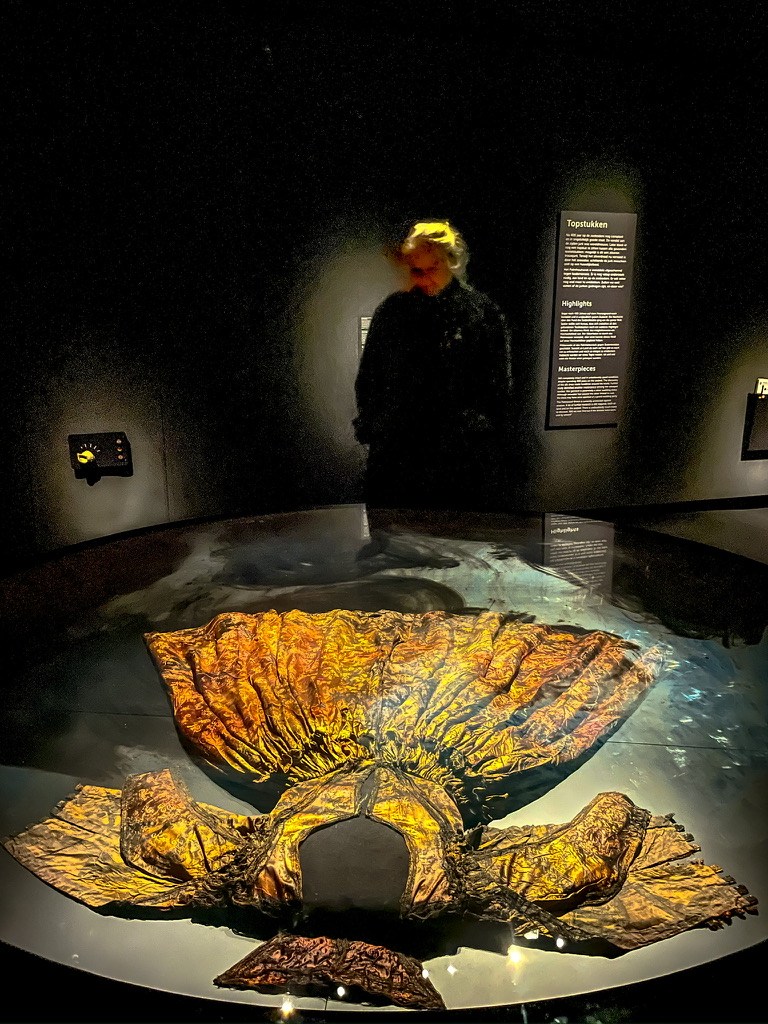 vrouw in een donkere ruimte kijkt naar een tentoongestelde jurk