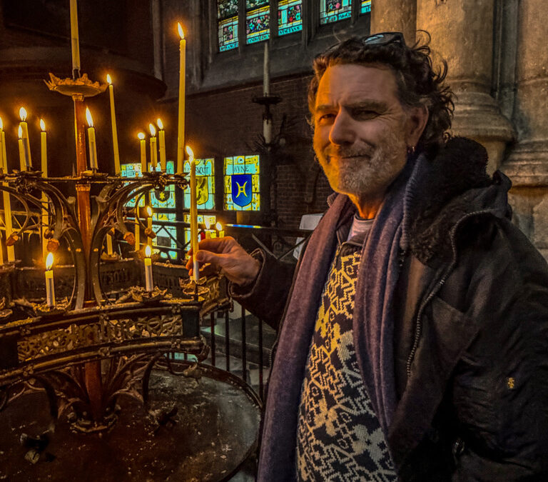 man staat in een kerk en steekt een kaars aan