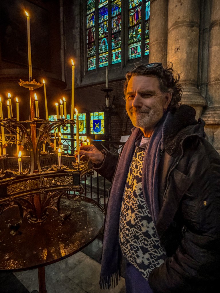 man staat in een kerk en steekt een kaars aan
